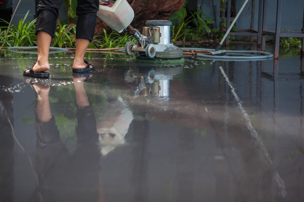 Person cleaning a flooded floor with a washing machine