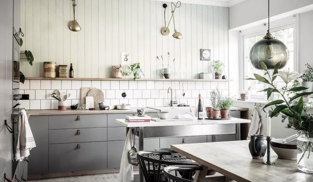 White and grey farmhouse kitchen with work table, dining area, shiplap wall partly covered with square tiles