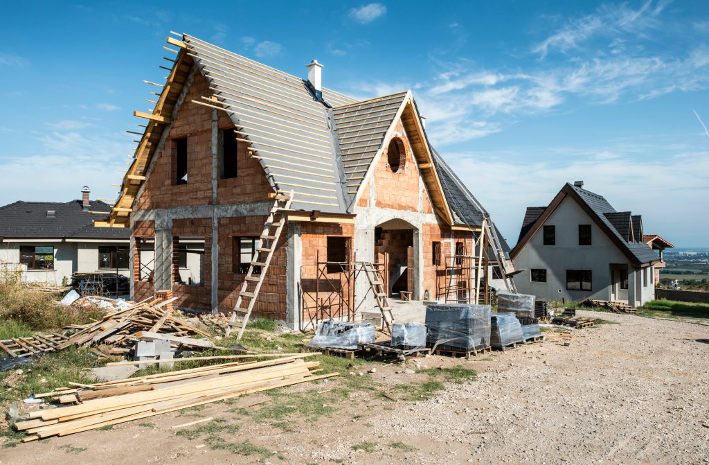 Gabled house under construction, with scaffolding and ladder on a treeless site