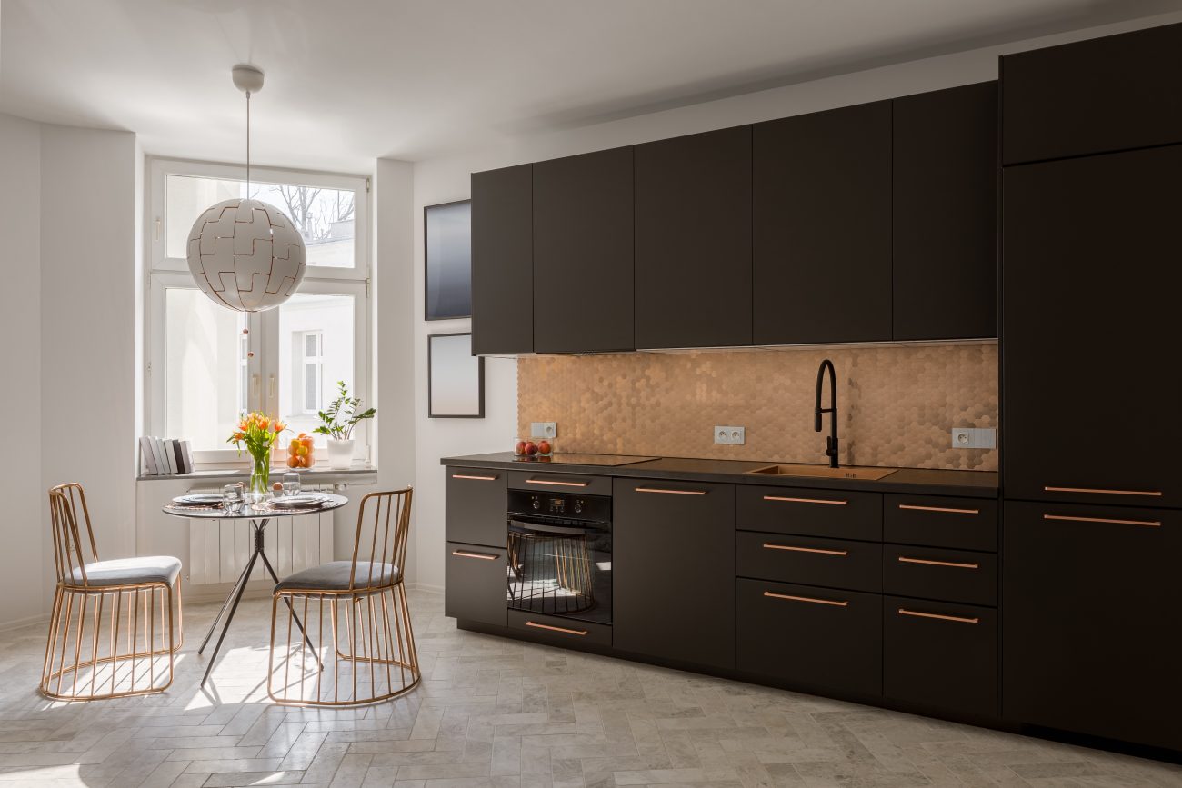 Modern black kitchen with copper details, round dining table and two elegant copper chairs