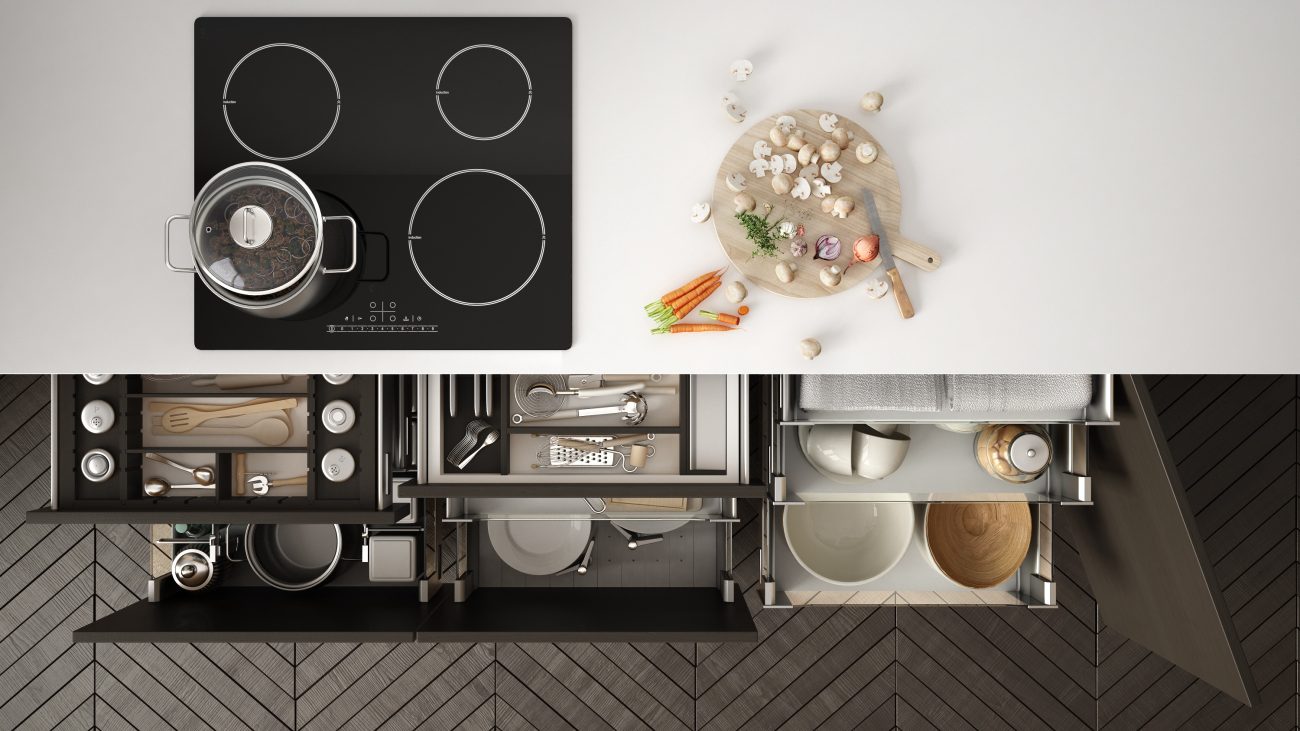 Overhead view of a kitchen counter including a built-in stove and open drawers filled with pots and utensils