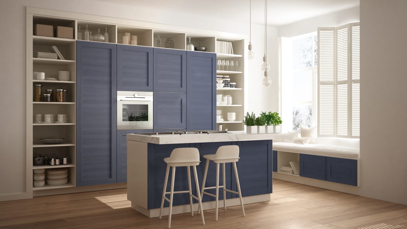 In a modern kitchen flooded with light, denim blue cabinets, open shelves, window seat and wood floor