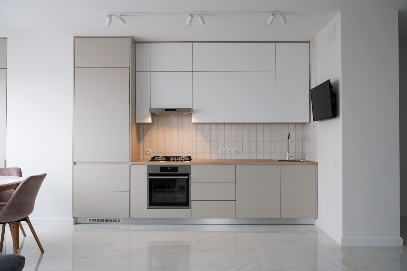 Modern kitchen with white and pale grey cabinets, paper fold effect backsplash and white marble floor tiles