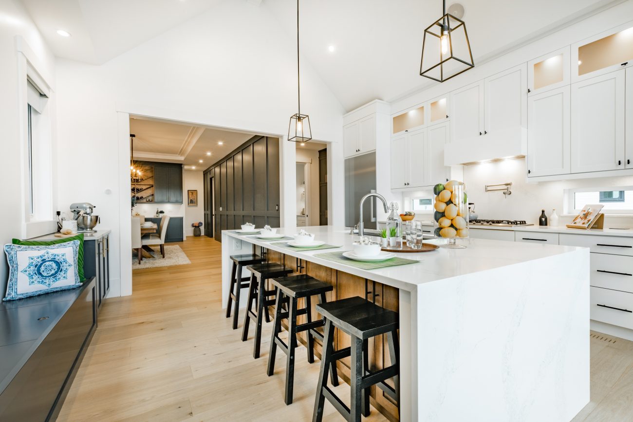 Spacious modern white kitchen with large island, four place settings and pendant lights