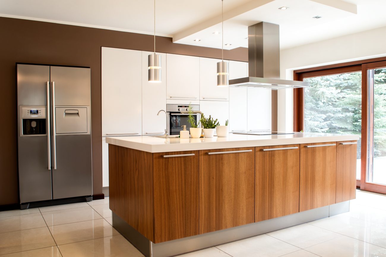 Modern kitchen with teak center island, white built-in cabinets and large patio doors