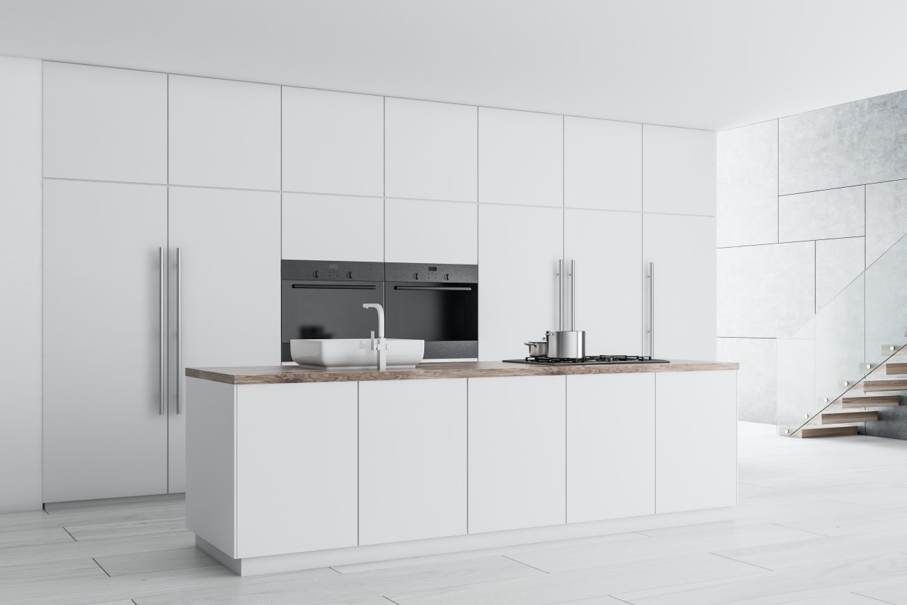 Modern kitchen with minimalist white countertops and cupboards, and a concrete white floor 