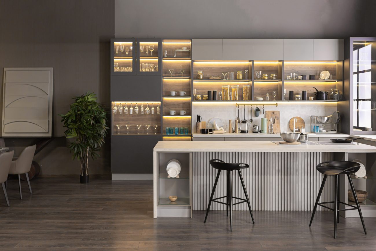 Wall-mounted storage unit with exposed and illuminated glassware in a grey-toned kitchen