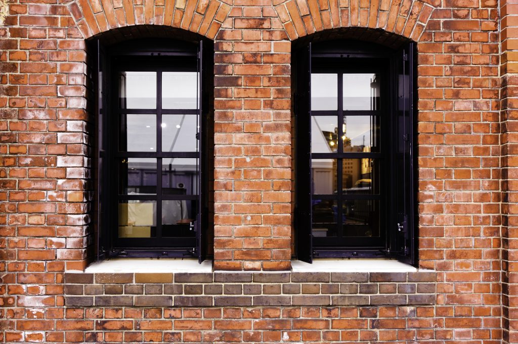 Red brick wall damaged by efflorescence, two checkered windows