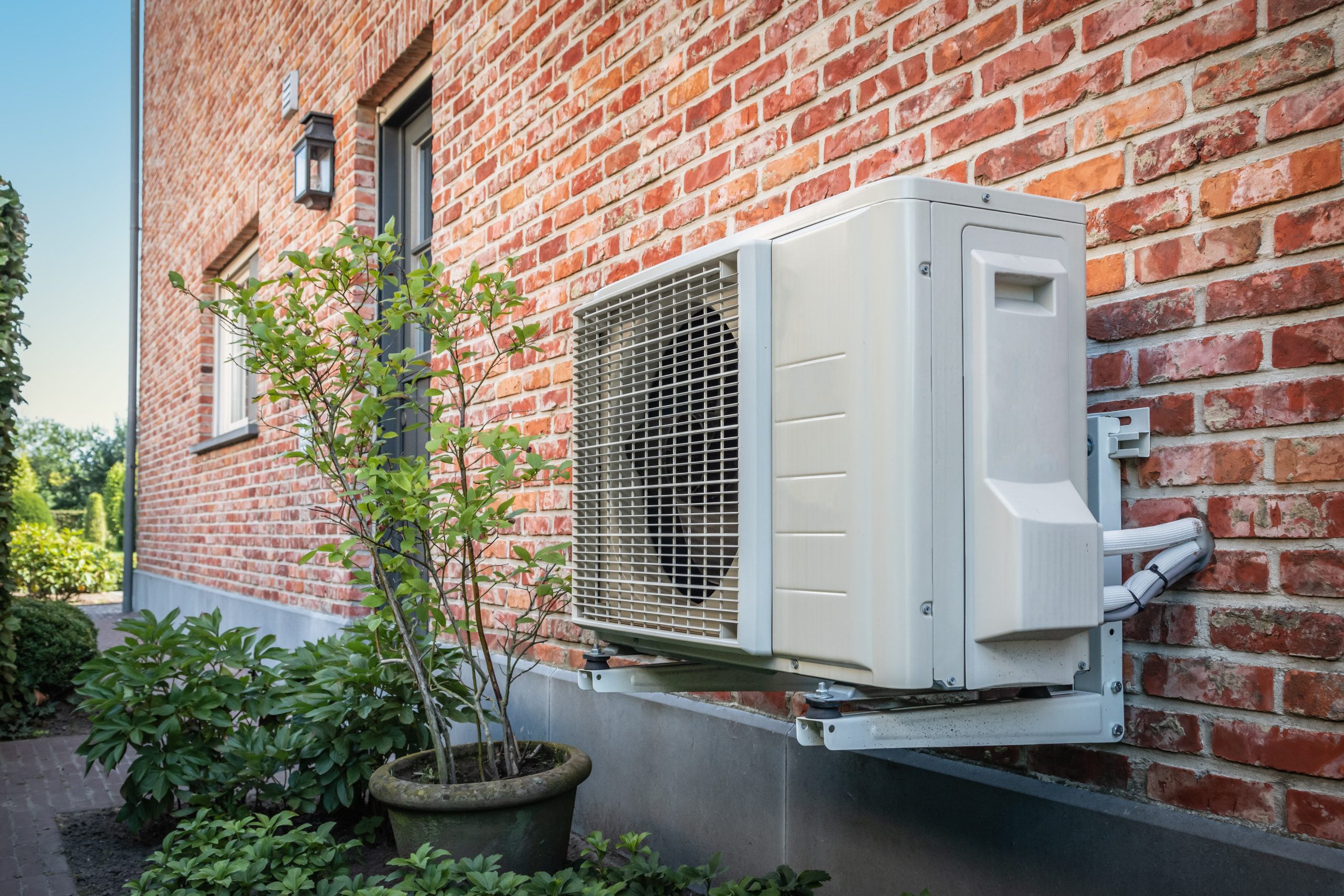 Outdoor heat pump unit attached to a brick wall