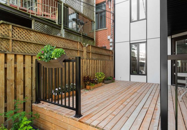 A cozy backyard porch with a black railing