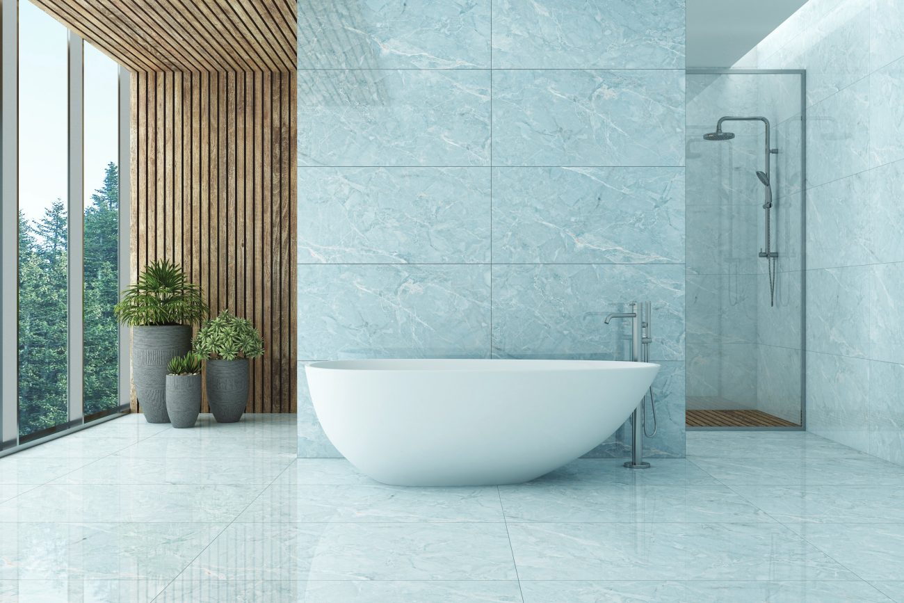 Salle de bain au design minimaliste luxueux, avec baignoire autoportante contre une paroi en marbre bleu pâle, pan de mur et plafond en lattes de bois, douche à pomme effet pluie séparée par une cloison en verre et plantes en pots près de la baie vitrée