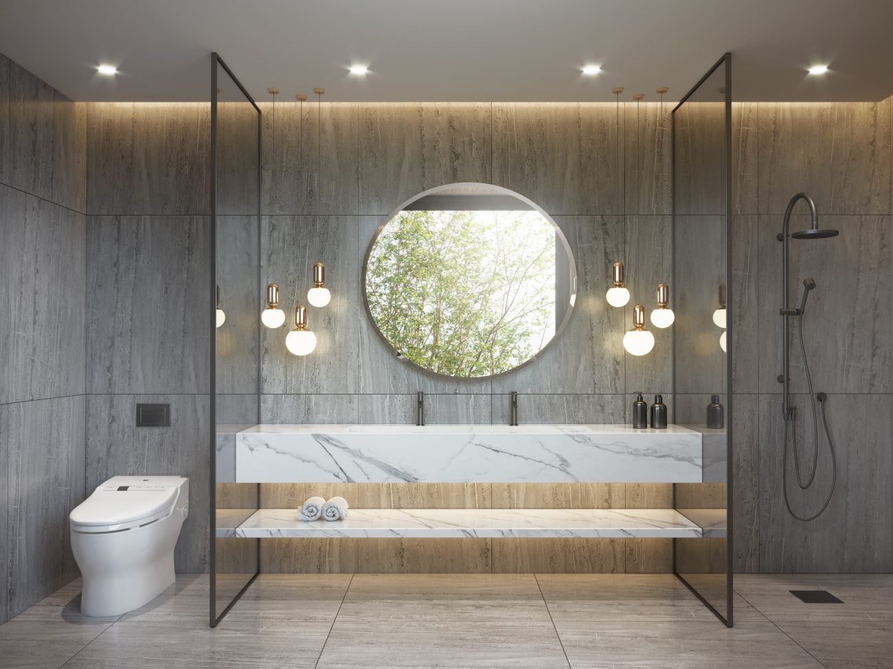 Salle de bain luxueuse en marbre gris, divisée en trois zones par des cloisons en verre : la zone toilette blanche, la zone meuble-lavabo avec étagère suspendue, luminaires globes de verre opaque et miroir rond, et enfin, la douche à l’italienne