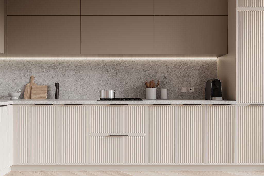 Beige textured cabinets and drawers in a kitchen with gray backsplash