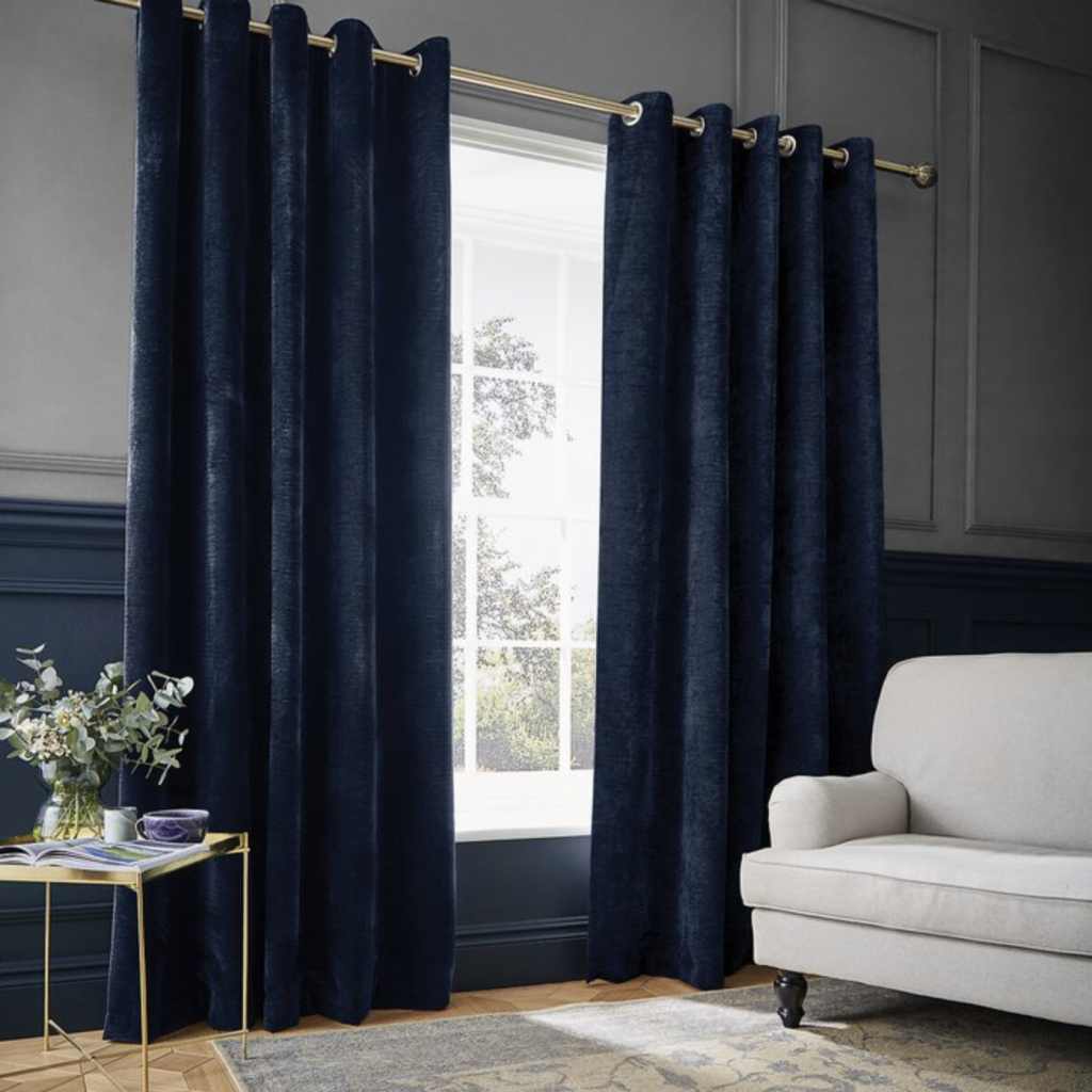 Insulating thermic navy blue curtains in a chic living room with white couch and gold metal table