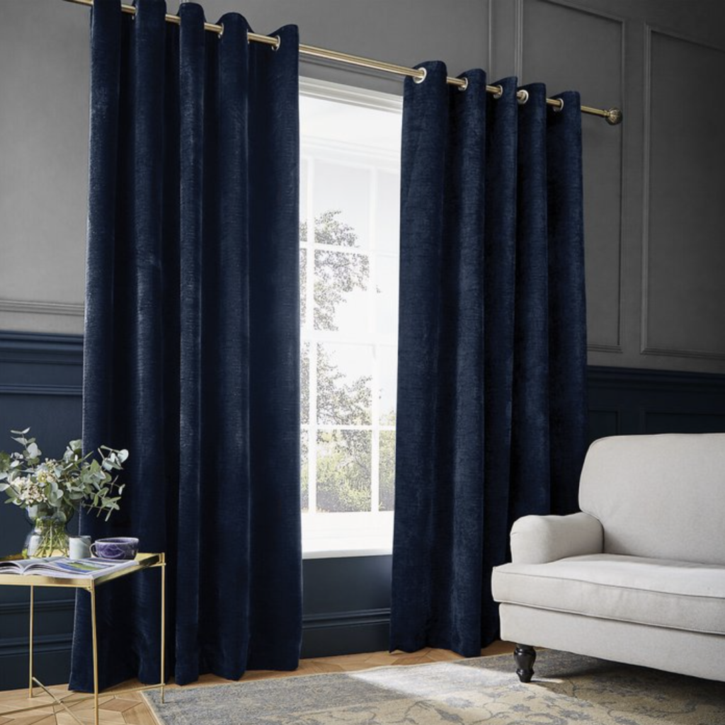 Rideaux thermiques bleu marine pour isoler les fenêtres d’un salon chic avec canapé blanc et table en métal doré