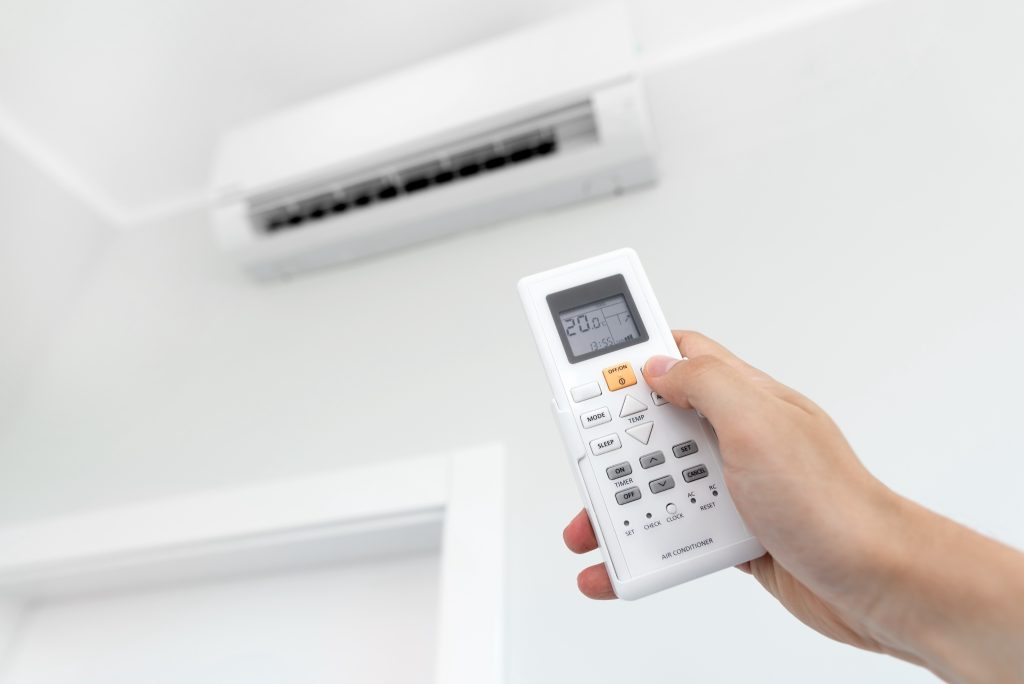 Hand holding remote control of a wall-mounted air conditioner