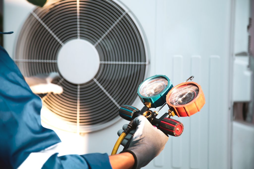 Air conditioner technician using manifold gauge checking refrigerant for filling home air conditioning unit