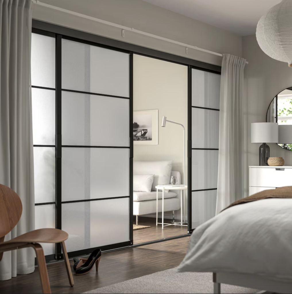 Portes coulissantes de style japonais en verre dépoli et cadre noir, séparant une chambre à coucher et un salon