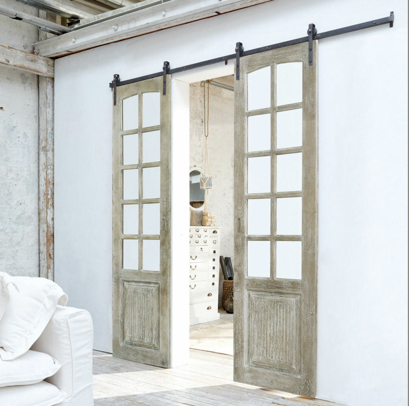 Sliding barn French doors in patinated wood, separating two rooms in a loft-style space