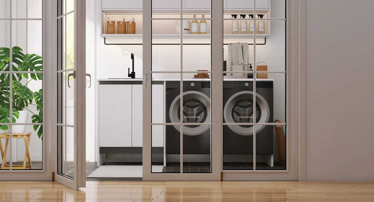 White frame glass sliding French doors of laundry room with black washing machines, cabinet, cupboard, sink and monstera plant