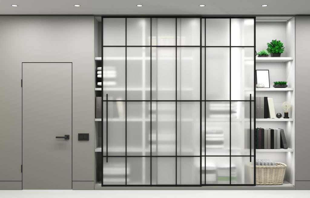 Frosted glass sliding doors with black metal lattice, in front of a shelved closet