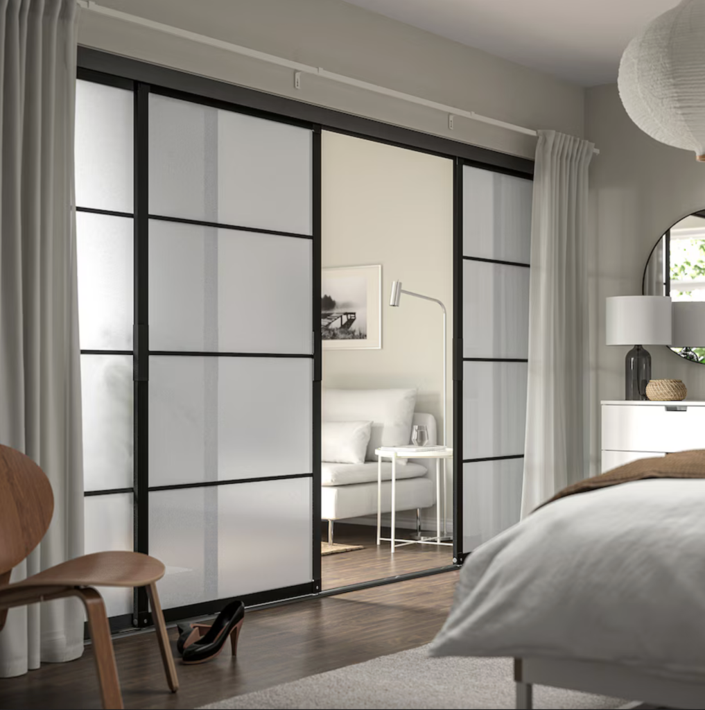 Japanese-style sliding doors with frosted glass and black frame, separating a bedroom and a living room