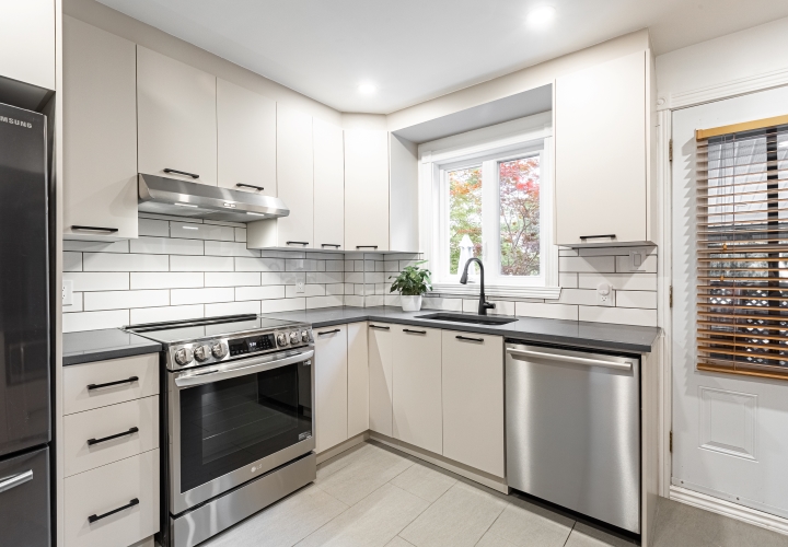 Classic white kitchen with view of white cabinets, white ceramic floor and white door.