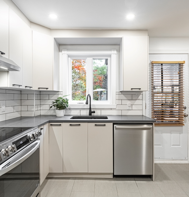 Classic white kitchen with view of white cupboards, white ceramic floor and gray stone peninsula.