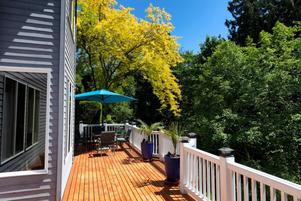 Terrasse en cèdre teinte naturelle avec garde-corps blancs et arbres matures à proximité