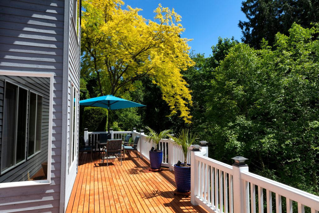 Natural-toned cedar terrace with white railings and mature trees nearby