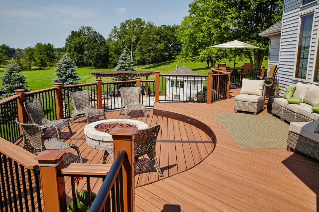 Red-brown composite deck with coordinated railings, gray furniture and a fire pit