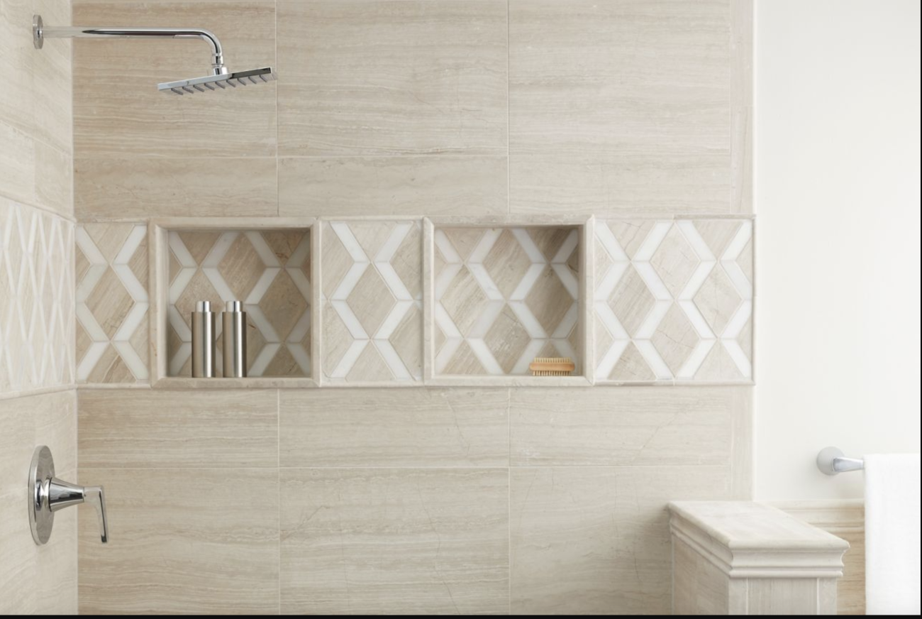 Inside a shower with a square showerhead, wall covered with beige limestone tiles, two accessory niches highlighted with white ceramic tiles in a zigzag pattern