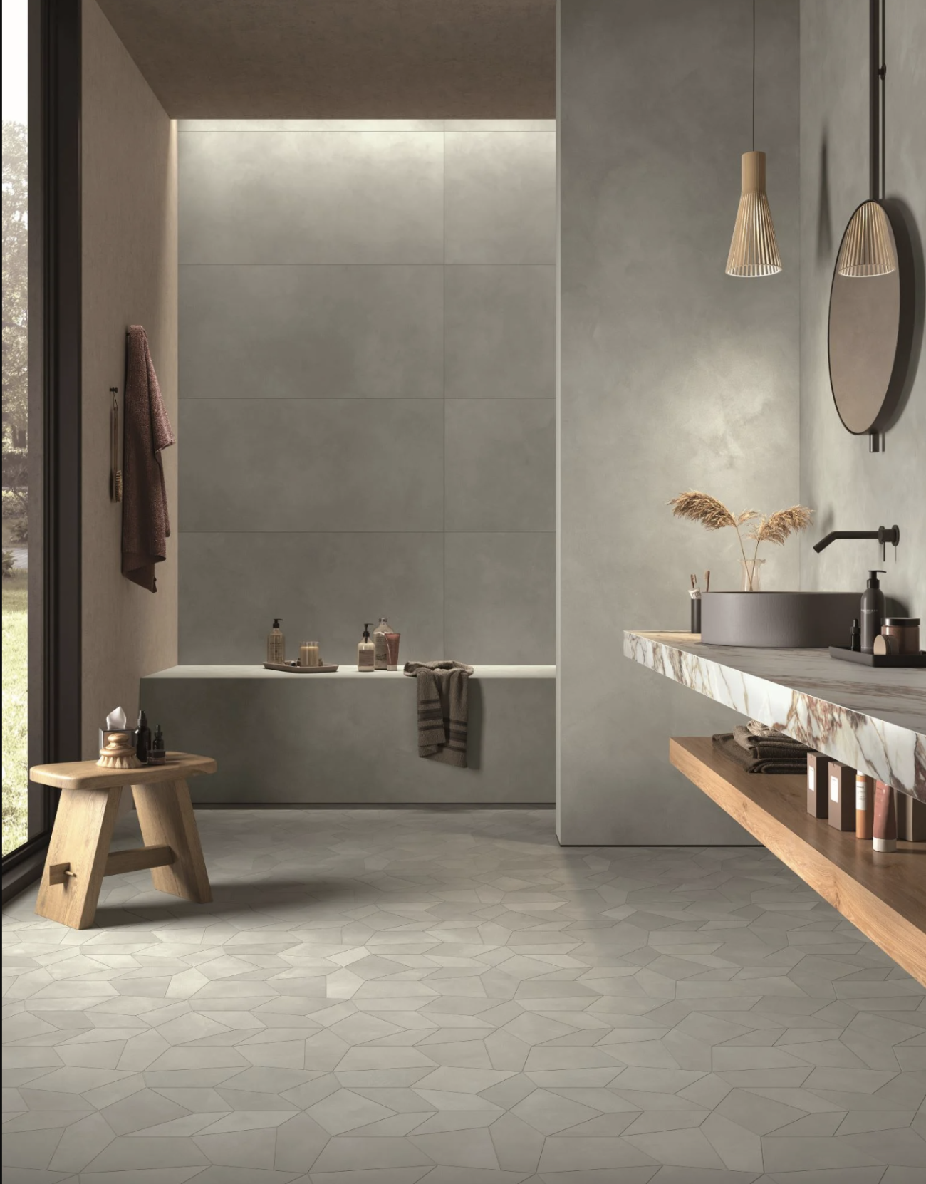 Japandi-style bathroom in taupe color, with a small pale wooden bench, floating marble countertop, large slate tiles on the wall, and a floor covered with tiles of various geometric shapes