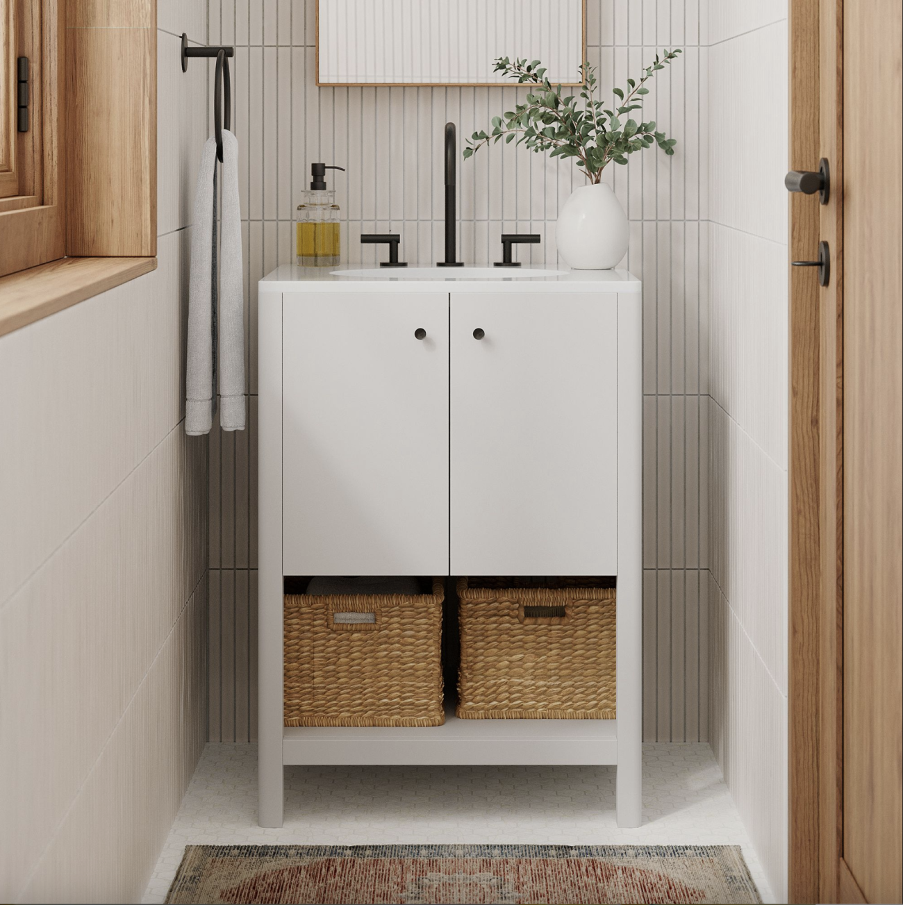 In a small bathroom, two-door vanity unit decorated with a soap dispenser, eucalyptus branch, and two woven storage baskets, wall covered with vertically placed rectangular white tiles