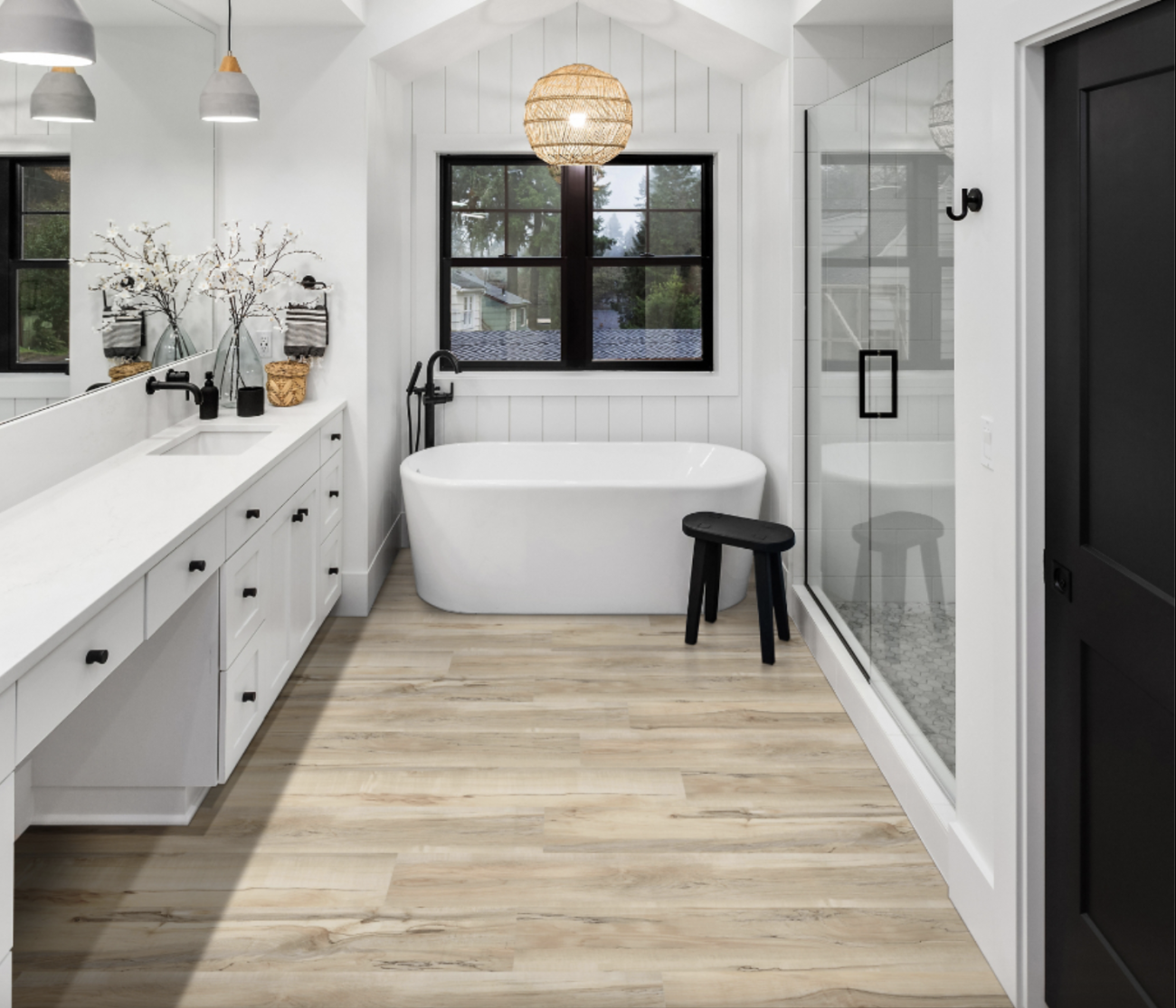 Salle de bain mélangeant les styles farmhouse et japonais, avec baignoire ovale dans une alcôve lambrissée, tabouret de bain, suspension globe en rotin, carrelage en vinyle imitant le bois, meuble-lavabo à plusieurs tiroirs, vaste douche à deux portes vitrées