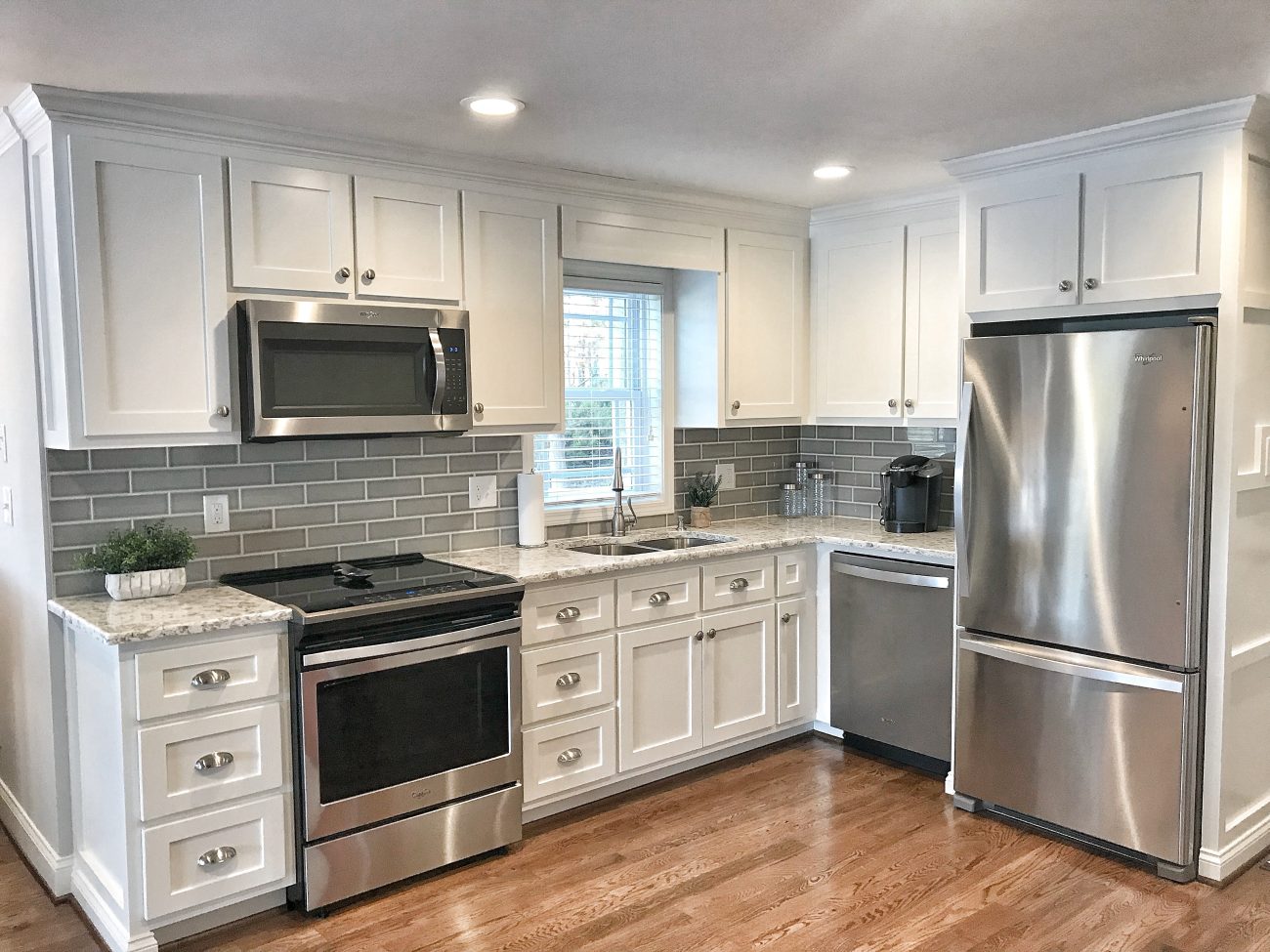 Farmhouse kitchen with pearl grey cabinets, dark grey metro tiles backsplash, stainless steel appliances and wood floor