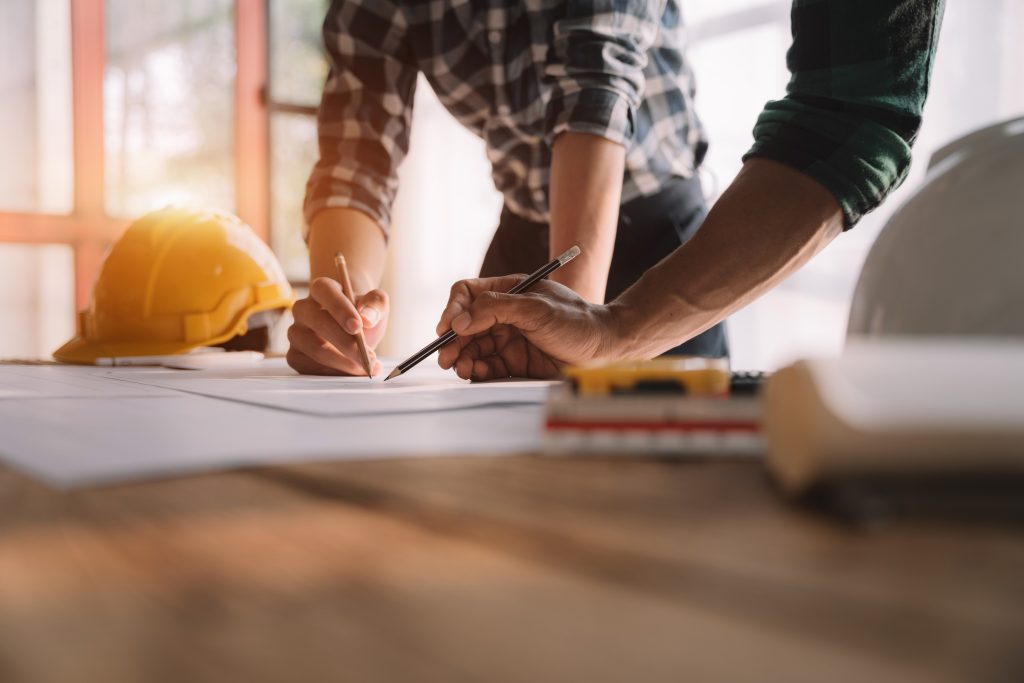 A reliable contractor is writing on a plan with a wooden pencil