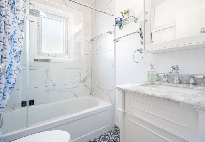 Classic white bathroom with view of white ceramic bathtub and shower and white quartz countertop