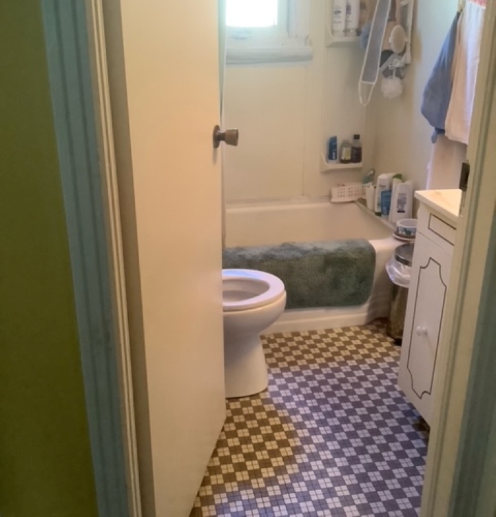 Salle de bain blanche et classique défraîchie avec vue sur baignoire, toilette et plancher de céramique en damier