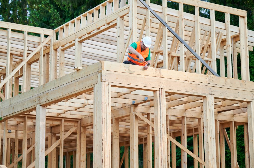 A carpenter works on the frame of a house under construction