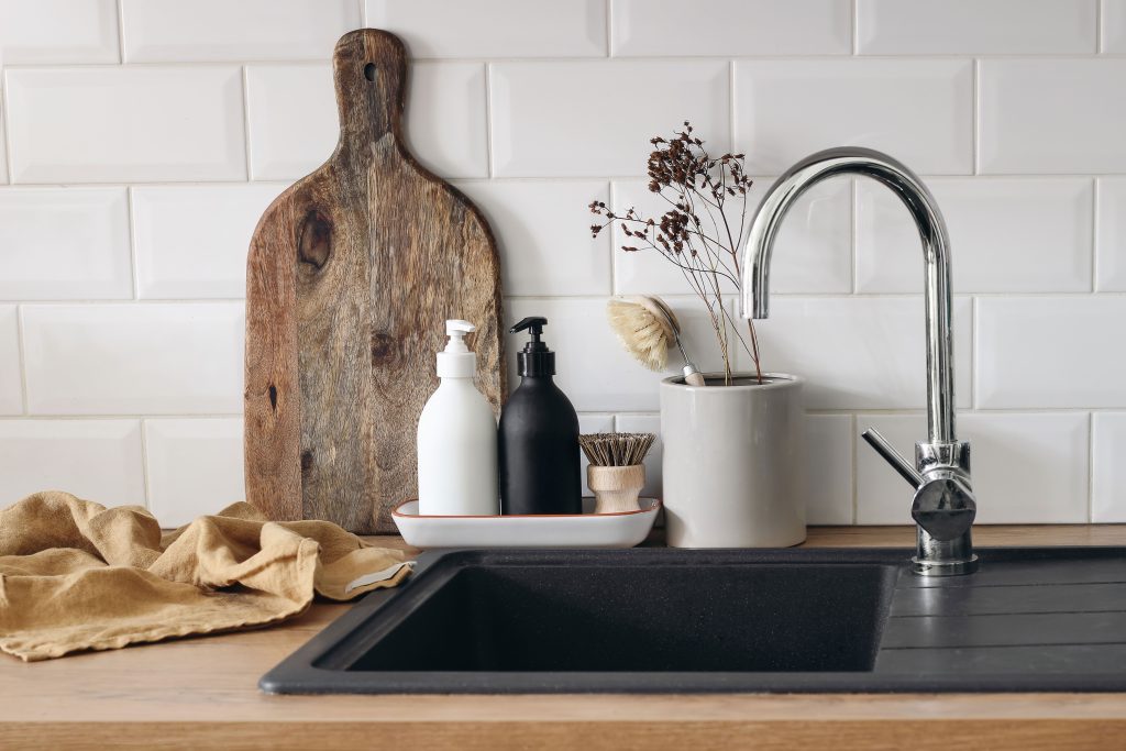 Decorative board, soap dispensers and jar on wooden kitchen countertop  