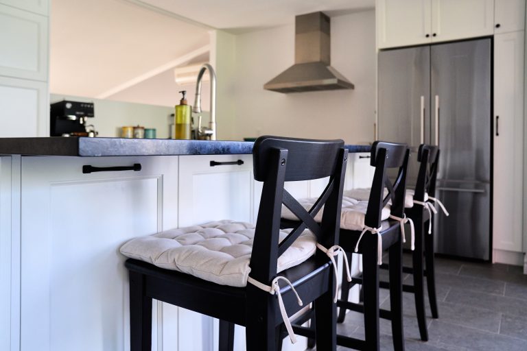 Black counter stools with grey cushions in front of a kitchen island