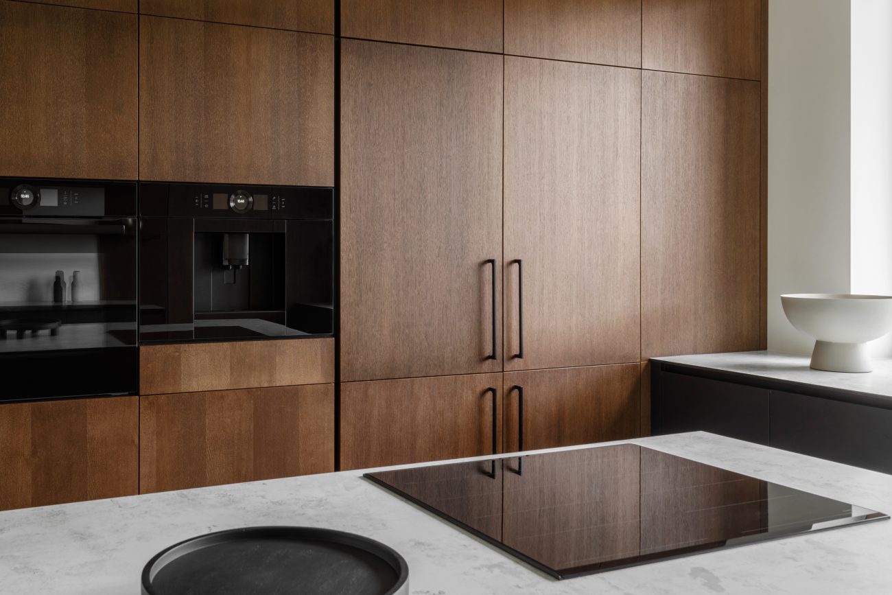 Modern kitchen with black and wood surfaces, marble island and built-in appliances