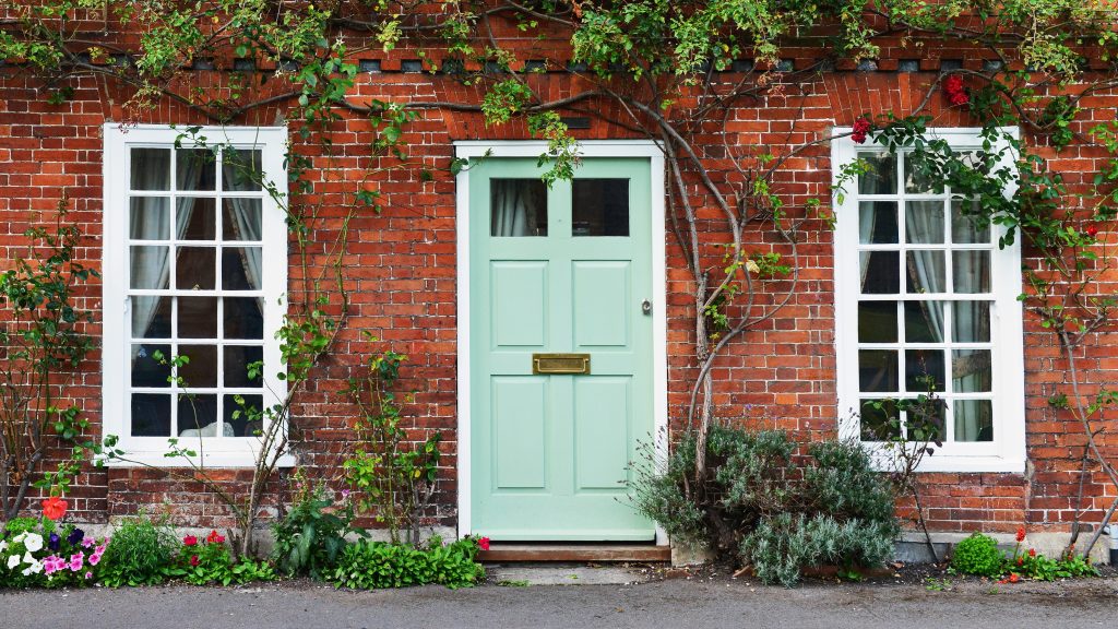 Une porte de couleur pistache sur une maison de briques