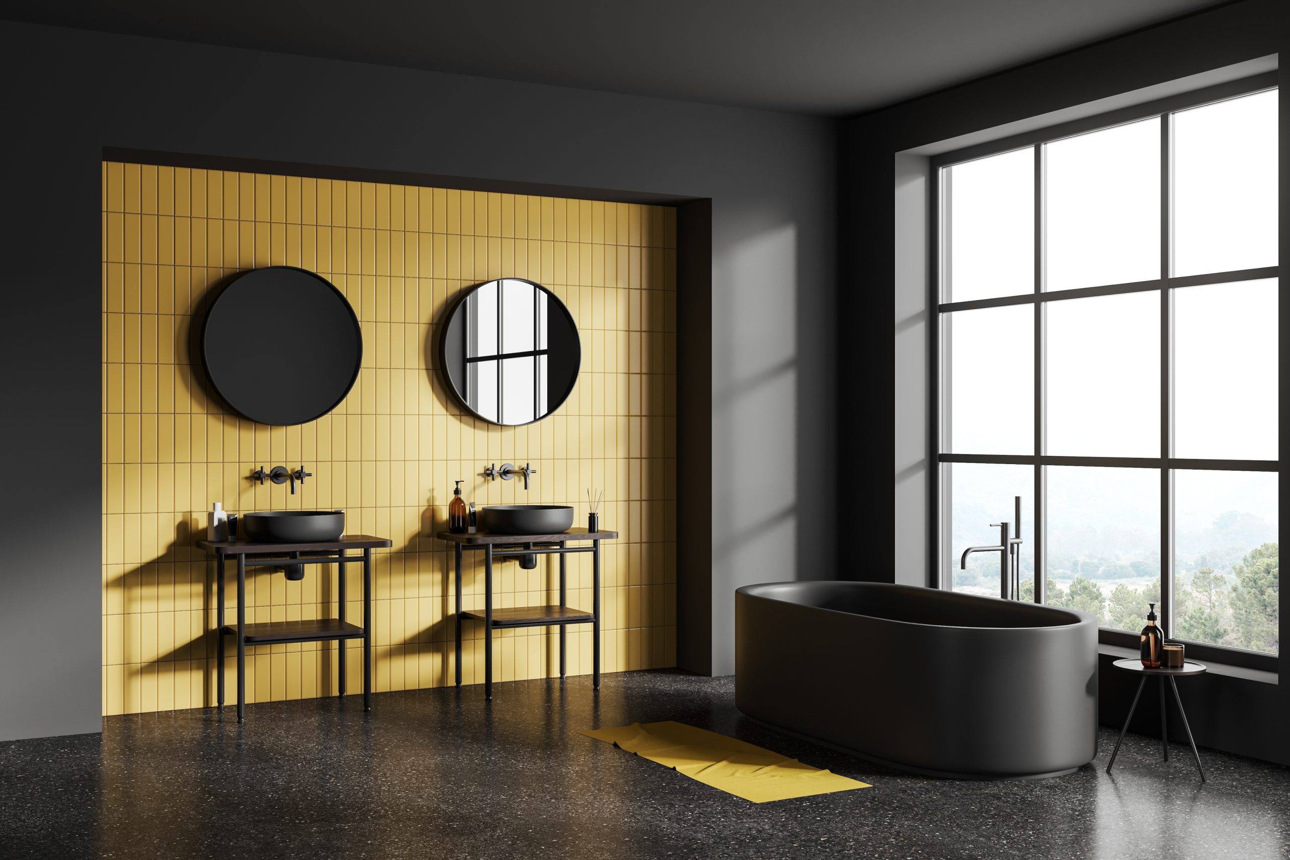 Bright bathroom thanks to generous industrial-style windows and an accent wall with vertical yellow tiles, everything else is black including the speckled concrete floor, freestanding bathtub, two vessel sinks on console tables