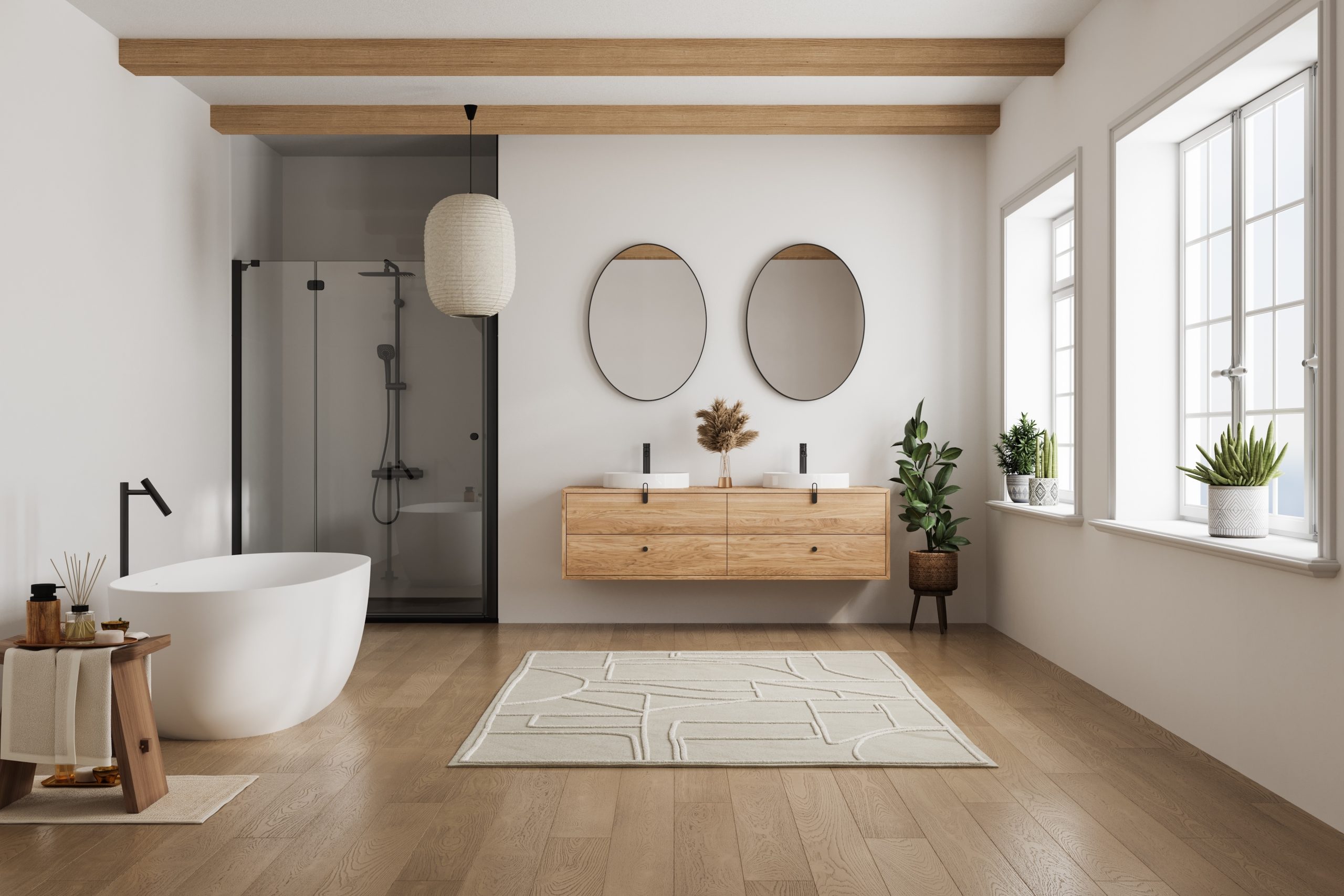 Bright Scandinavian-style bathroom with light wood floor, vanity, and beams, mullioned windows, two oval mirrors, white freestanding bathtub, bath mat, low wooden stool with beauty products, white rice paper lantern lamp, black hardware shower